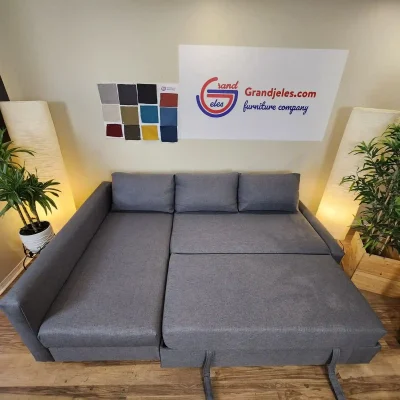 Canapé-lit IKEA Friheten gris remis à neuf avec rangement, déplié en position lit dans une pièce décorée.
